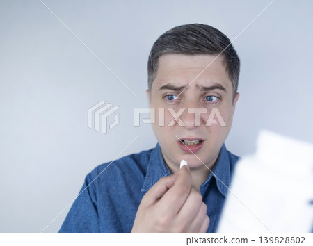 Man suffering from phagophobia struggling to swallow pill. Caucasian male looking anxious and scared before taking medication, experiencing fear of choking or swallowing difficulties. Man suffering from phagophobia struggling to swallow pill. Caucasian male looking anxious and scared before taking medication, experiencing fear of choking or swallowing difficulties. 139828802