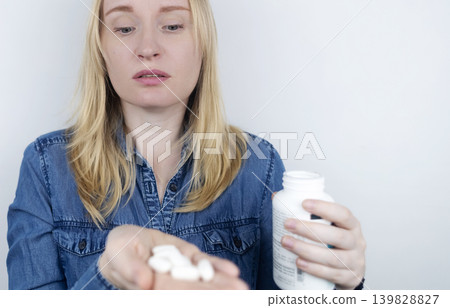 Woman suffering from phagophobia struggling to swallow a pill. Anxious female holding a medicine bottle, feeling fear, stress and difficulty swallowing medication. 139828827