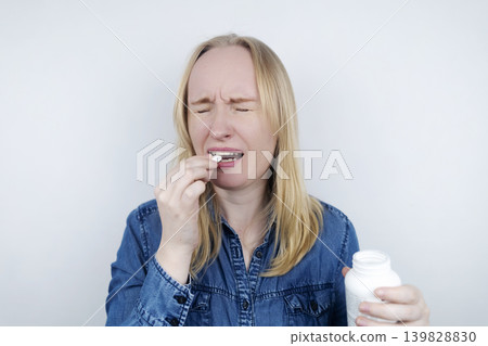 Woman suffering from phagophobia struggling to swallow a pill. Anxious female holding a medicine bottle, feeling fear, stress and difficulty swallowing medication. Woman suffering from phagophobia struggling to swallow a pill. Anxious female holding a medicine bottle, feeling fear, stress and difficulty swallowing medication. 139828830