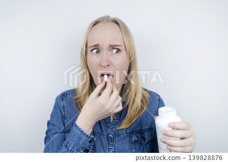 Woman suffering from phagophobia struggling to swallow a pill. Anxious female holding a medicine bottle, feeling fear, stress and difficulty swallowing medication. Woman suffering from phagophobia struggling to swallow a pill. Anxious female holding a medicine bottle, feeling fear, stress and difficulty swallowing medication. 139828876