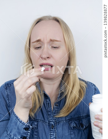 Woman suffering from phagophobia struggling to swallow a pill. Anxious female holding a medicine bottle, feeling fear, stress and difficulty swallowing medication. Woman suffering from phagophobia struggling to swallow a pill. Anxious female holding a medicine bottle, feeling fear, stress and difficulty swallowing medication. 139828877