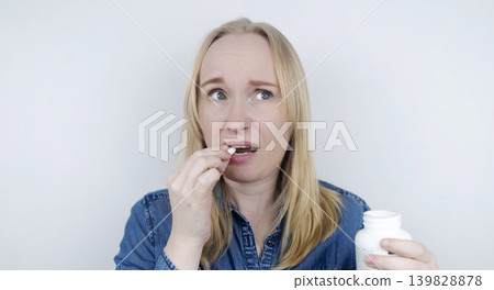 Woman suffering from phagophobia struggling to swallow a pill. Anxious female holding a medicine bottle, feeling fear, stress and difficulty swallowing medication. 139828878