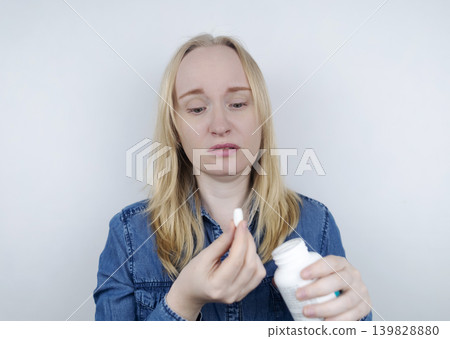 Woman suffering from phagophobia struggling to swallow a pill. Anxious female holding a medicine bottle, feeling fear, stress and difficulty swallowing medication. Woman suffering from phagophobia struggling to swallow a pill. Anxious female holding a medicine bottle, feeling fear, stress and difficulty swallowing medication. 139828880