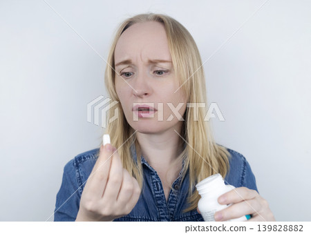 Woman suffering from phagophobia struggling to swallow a pill. Anxious female holding a medicine bottle, feeling fear, stress and difficulty swallowing medication. 139828882
