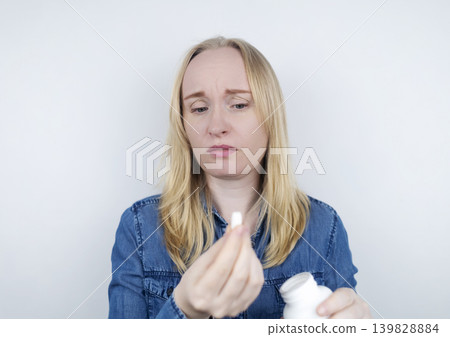 Woman suffering from phagophobia struggling to swallow a pill. Anxious female holding a medicine bottle, feeling fear, stress and difficulty swallowing medication. 139828884