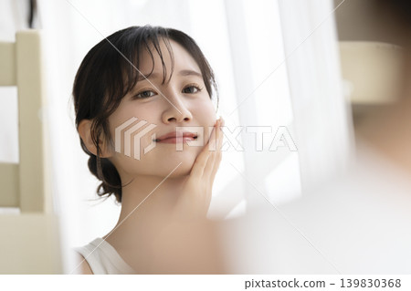 一位年輕女子對著鏡子微笑。 139830368
