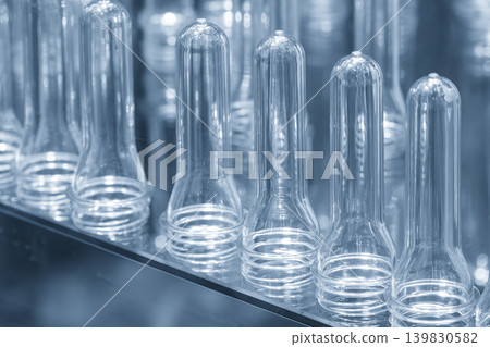 Close-up of a group of clear PET plastic preform shapes, the raw material for drinking water bottle mass production lines. Close-up of a group of clear PET plastic preform shapes, the raw material for drinking water bottle mass production lines. 139830582