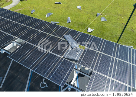 Hurricane wind damage to solar panels installed as shade roof over parking lot for parked electric cars. Failing of photovoltaic technology integrated in urban infrastructure 139830624