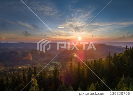Colorful sunset in wild mountains. Dark pine forest illuminated with bright setting sun. Beautiful nature landscape Colorful sunset in wild mountains. Dark pine forest illuminated with bright setting sun. Beautiful nature landscape 139830706