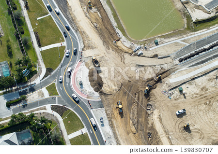 Industrial construction roadworks at roundabout intersection with moving cars in Venice, Florida. Development of urban circular transportation crossroads Industrial construction roadworks at roundabout intersection with moving cars in Venice, Florida. Development of urban circular transportation crossroads 139830707