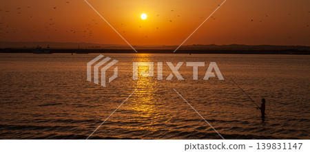 Silhouettes of fishermen casting rods on beach at sunset in southern Spain 139831147
