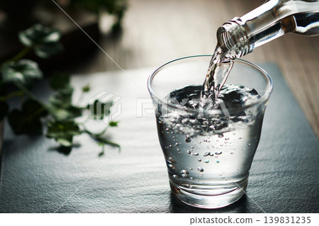 將礦泉水倒入玻璃杯中 將礦泉水倒入玻璃杯中 139831235