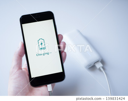 A smartphone charging with a white mobile battery (screen design is original). A smartphone charging with a white mobile battery (screen design is original). 139831424