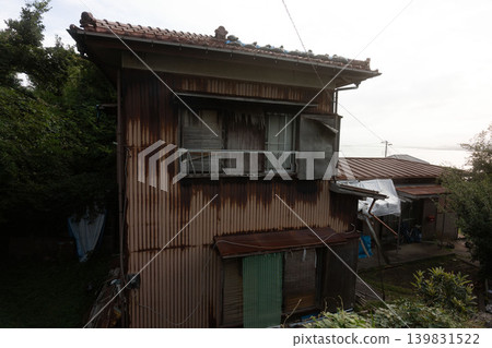 Showa Retro Nostalgia: A peaceful port town landscape with weathered tiled roofs and bamboo blinds. 139831522