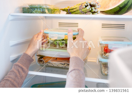 Woman Organizing Healthy Meal Prep Containers in Refrigerator at Home Woman Organizing Healthy Meal Prep Containers in Refrigerator at Home 139831561
