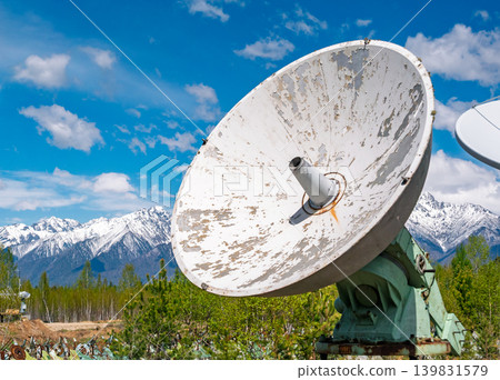White radio telescope at the Siberian Solar Radio Telescope facility capturing solar activity near snow-capped mountains on a bright day White radio telescope at the Siberian Solar Radio Telescope facility capturing solar activity near snow-capped mountains on a bright day 139831579