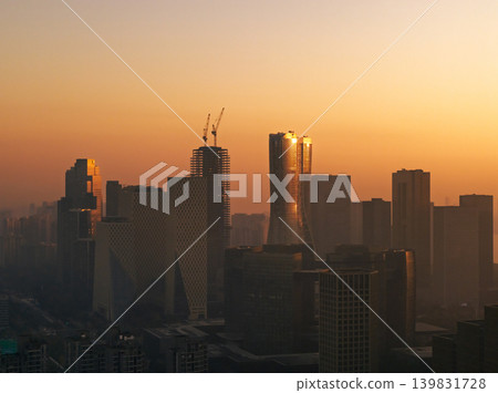 Aerial perspective capturing the sunrise over Hangzhou, China. Silhouetted buildings are visible against the vibrant red and orange sky. City view at dawn with rising sun. Aerial perspective capturing the sunrise over Hangzhou, China. Silhouetted buildings are visible against the vibrant red and orange sky. City view at dawn with rising sun. 139831728
