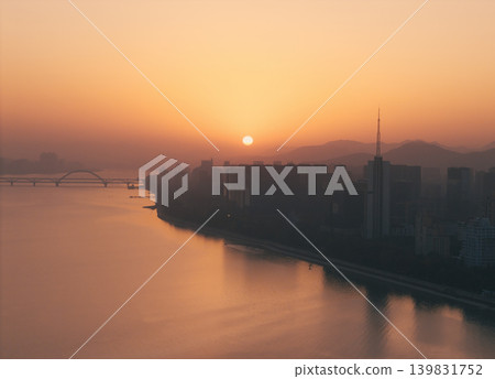 Beautiful sunset over the river with orange glow reflecting on water and bridges Beautiful sunset over the river with orange glow reflecting on water and bridges 139831752