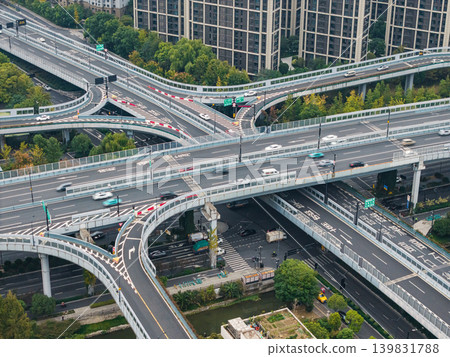 Multilevel highway interchange with numerous vehicles traversing elevated roads and ramps in a dense city environment Multilevel highway interchange with numerous vehicles traversing elevated roads and ramps in a dense city environment 139831788