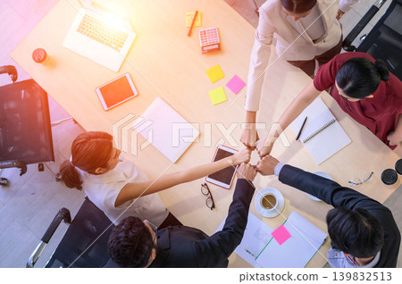 Top view of business people clapping hands together over table, Below graphs placed on the desk. Young businessman and businesswoman stack of hands showing unity and teamwork support. Top view of business people clapping hands together over table, Below graphs placed on the desk. Young businessman and businesswoman stack of hands showing unity and teamwork support. 139832513