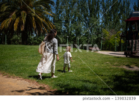 Mother walking with young son in a sunny park enjoying a relaxed family afternoon together Mother walking with young son in a sunny park enjoying a relaxed family afternoon together 139832839