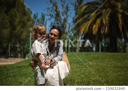 Mother and young son enjoying a happy sunny day together at a green park Mother and young son enjoying a happy sunny day together at a green park 139832840
