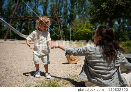 Mother and son enjoying a happy sunny day together at a kids park playground Mother and son enjoying a happy sunny day together at a kids park playground 139832860