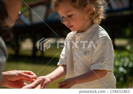 Mother helping young son outdoors in a sunny kids park on a happy family day Mother helping young son outdoors in a sunny kids park on a happy family day 139832863