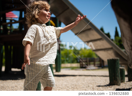 Mother and son enjoying a sunny day at the playground with a happy toddler reaching out Mother and son enjoying a sunny day at the playground with a happy toddler reaching out 139832880