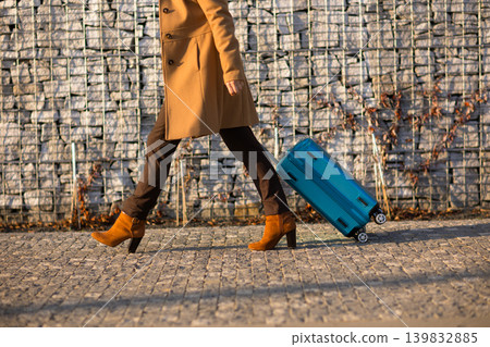 Detail View of a Traveler Pulling a Blue Suitcase on Cobblestone 139832885