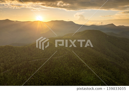 Winding parkway road in mountain forest with green canopies in summertime evening. Driving in North Carolina wild woods nature in summer 139833035