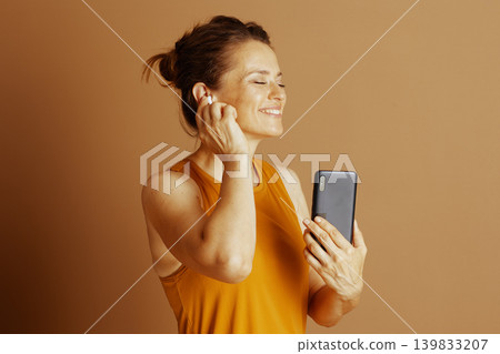 Woman Adjusting Earbud with Joyful Smile Woman Adjusting Earbud with Joyful Smile 139833207
