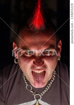 Punk rock musician with red crest hairstyle and piercings portrait 139833229