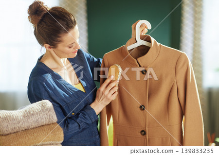 Woman Carefully Brushing Camel Coat for Sustainable Wardrobe Woman Carefully Brushing Camel Coat for Sustainable Wardrobe 139833235
