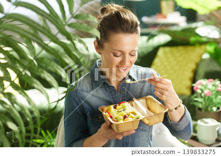 Smiling Woman Holding a Piece of Fruit on a Wooden Fork 139833275