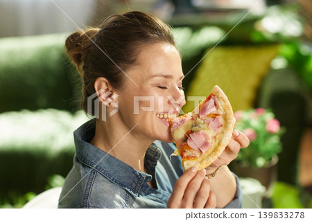 Woman Taking a Bite of Savory Pizza at Home Woman Taking a Bite of Savory Pizza at Home 139833278