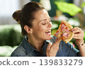 Cheerful Woman Enjoying Pizza Slice at Home 139833279