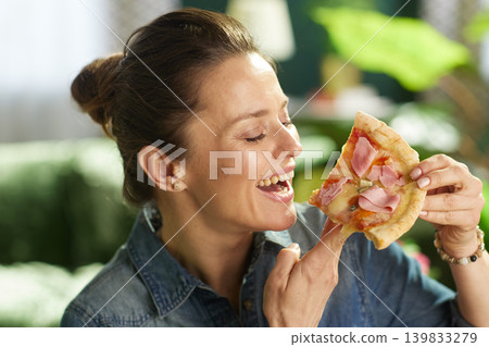 Cheerful Woman Enjoying Pizza Slice at Home Cheerful Woman Enjoying Pizza Slice at Home 139833279