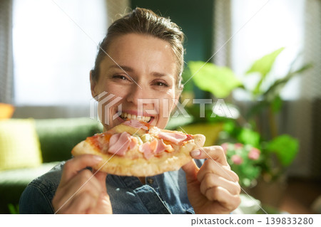 Smiling Woman Holding Pizza in a Cozy Living Room Smiling Woman Holding Pizza in a Cozy Living Room 139833280