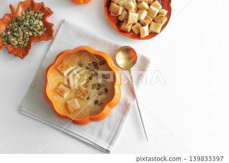 Creamy pumpkin soup with croutons and seeds, served in a pumpkin shaped bowl 139833397