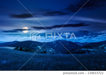 mountainous countryside landscape in summer at night. full moon over grassy field on a hillside. view of a forested mountain ridge in the distance. mysterious weather with cloudy sky mountainous countryside landscape in summer at night. full moon over grassy field on a hillside. view of a forested mountain ridge in the distance. mysterious weather with cloudy sky 139833722