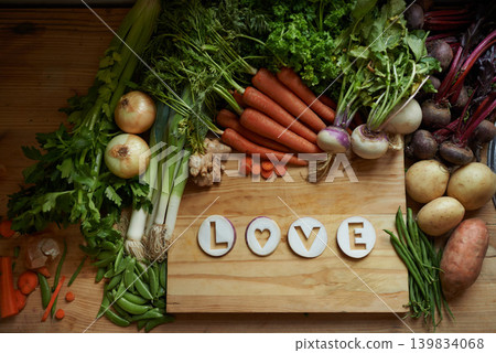 Food, chopping board and message for love, nutrition and cooking for wellbeing or eating. Home, above and vegetables for diet, health and vitamins in kitchen for vegan, vitality and top view Food, chopping board and message for love, nutrition and cooking for wellbeing or eating. Home, above and vegetables for diet, health and vitamins in kitchen for vegan, vitality and top view 139834068