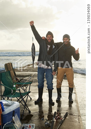Happy, portrait and men fishing at beach with pride for tuna catch on ocean pier at sunset. Fisherman, friends and smile holding fish in hand in nature at sea on holiday, adventure or vacation 139834069