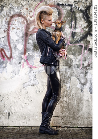 Woman, love and dog in edgy fashion with punk rock hairstyle, funky and bonding with chihuahua by graffiti wall. London, designer or leather jacket in urban town or care for pet animal by street art Woman, love and dog in edgy fashion with punk rock hairstyle, funky and bonding with chihuahua by graffiti wall. London, designer or leather jacket in urban town or care for pet animal by street art 139834205