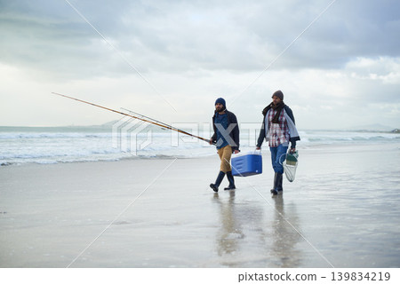 Winter, fishing and men walking on beach together with cooler, tackle box and holiday conversation. Ocean, fisherman or friends with rods, bait and tools in nature on morning vacation with cloudy sky Winter, fishing and men walking on beach together with cooler, tackle box and holiday conversation. Ocean, fisherman or friends with rods, bait and tools in nature on morning vacation with cloudy sky 139834219