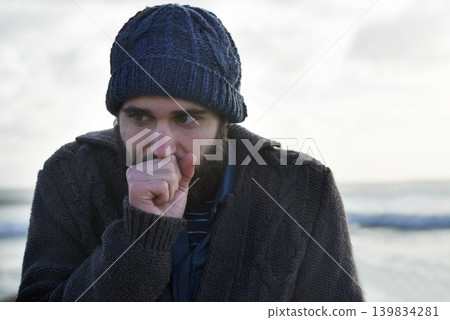 Winter, breathing and beach with man, thinking and cold weather with waves and freezing. Person, ocean and guy with wool jersey and cap with early morning activity and nature with vacation and travel Winter, breathing and beach with man, thinking and cold weather with waves and freezing. Person, ocean and guy with wool jersey and cap with early morning activity and nature with vacation and travel 139834281