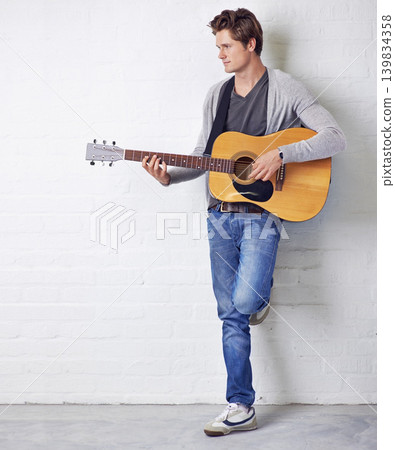 Man, guitar and musician with creativity and music, acoustic for entertainment and performance against wall background. Busker, artist and musical instrument for art, track or song with talent Man, guitar and musician with creativity and music, acoustic for entertainment and performance against wall background. Busker, artist and musical instrument for art, track or song with talent 139834358