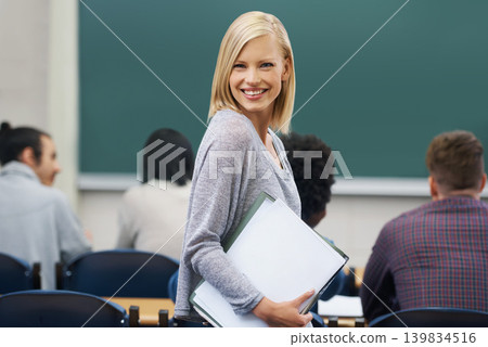 Woman, smile and portrait of teacher in classroom with students for learning, knowledge and development. Female lecturer, happy and confident with notebook for education, training or academic career Woman, smile and portrait of teacher in classroom with students for learning, knowledge and development. Female lecturer, happy and confident with notebook for education, training or academic career 139834516