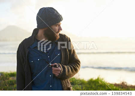 Man, pipe and thinking in nature by ocean for ideas, vision or planning on winter morning. Male person, sunrise and standing on grass by sea for relaxation, wondering or smoking with tobacco outdoors Man, pipe and thinking in nature by ocean for ideas, vision or planning on winter morning. Male person, sunrise and standing on grass by sea for relaxation, wondering or smoking with tobacco outdoors 139834543