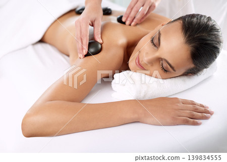 Hot stone, woman and hands massage shoulder for skincare, beauty and pamper body for wellness at luxury salon. Back, rocks and happy person at spa for treatment, relax or health with masseuse 139834555